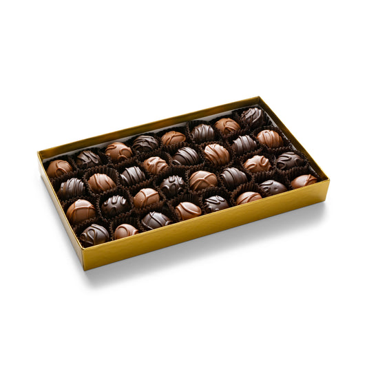 A gold gift box with assorted creams including vanilla, maple, mint, chocolate, raspberry and orange creams in milk and dark chocolate