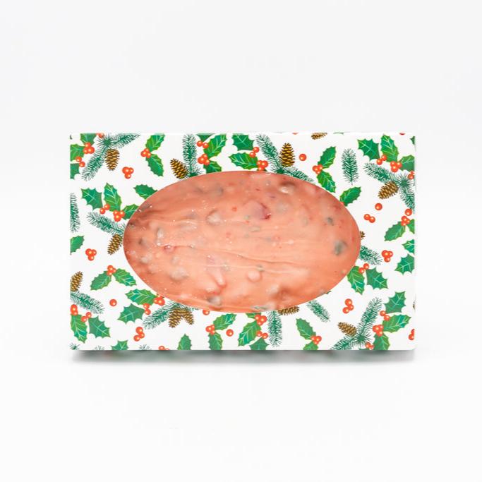 Pink peppermint stick bark nestled in a white and green box adorned with holly leaves