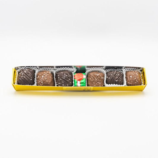 A gold gift box with a solid milk chocolate foil wrapped present and 6 total milk chocolate and dark chocolate sea salt caramels