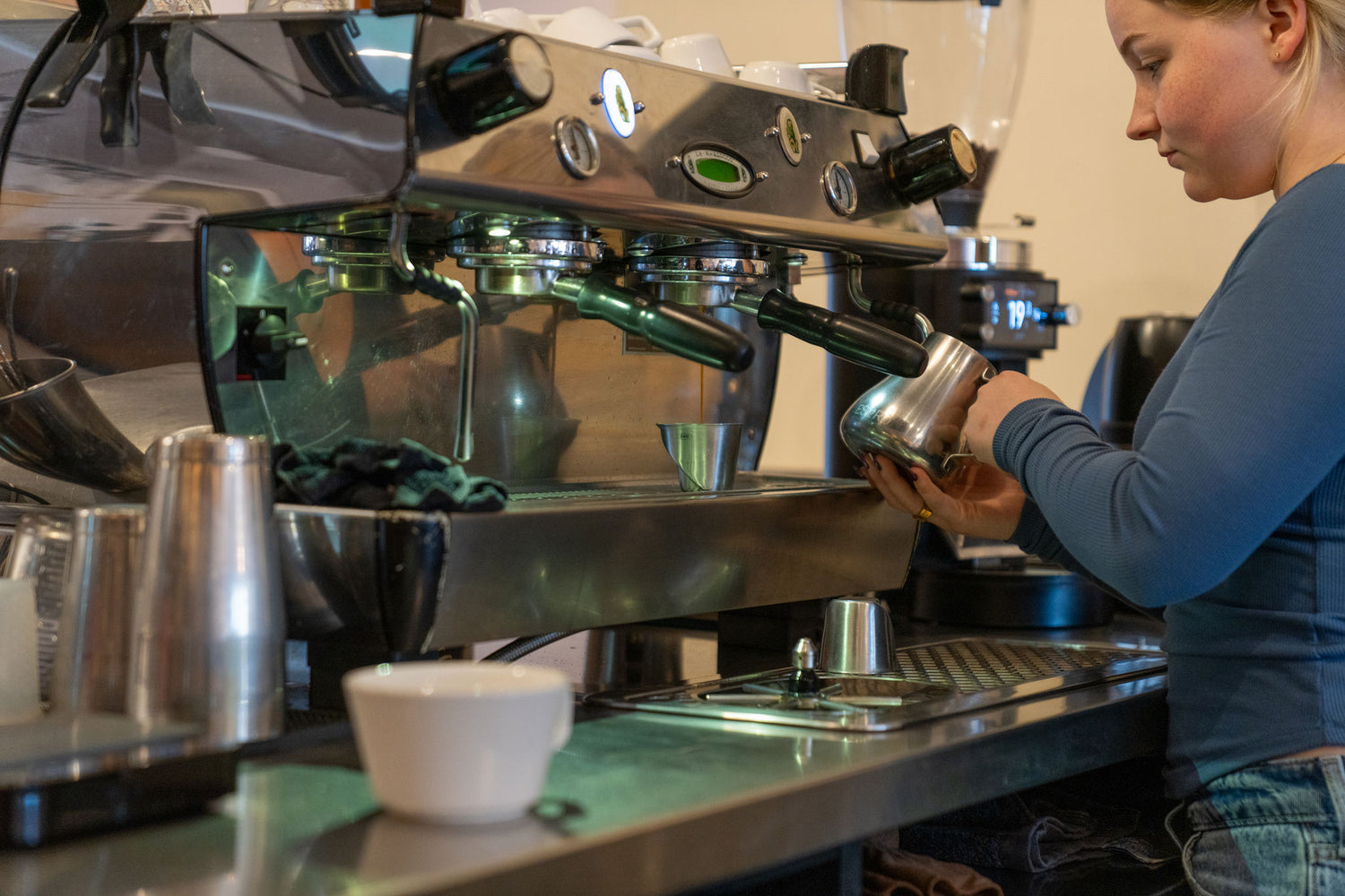 Person operating a coffee machine in a cafe setting. Making a specialty latte.